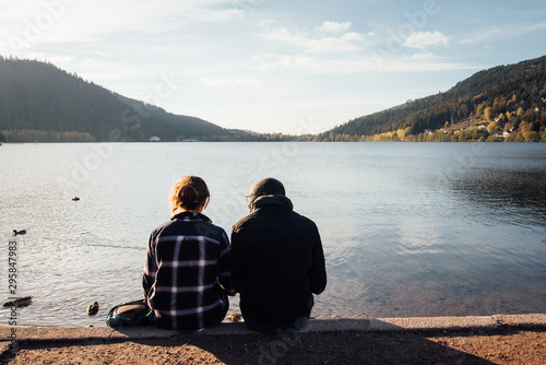 un couple d'amoureux devant le lac de Gérardmer. Des gens assis devant un lac. Des amoureux regardant un lac. Le lac de Gérardmer dans les Vosges.