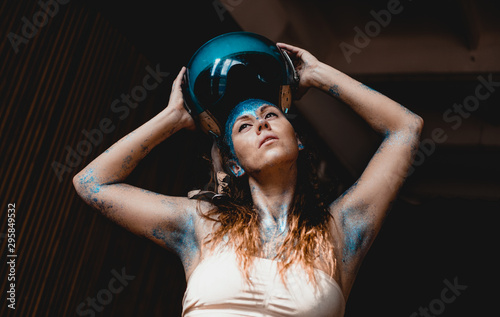 Woman motorcyclist put on crash helmet. Portrait of beautiful woman with blue sparkles on her face