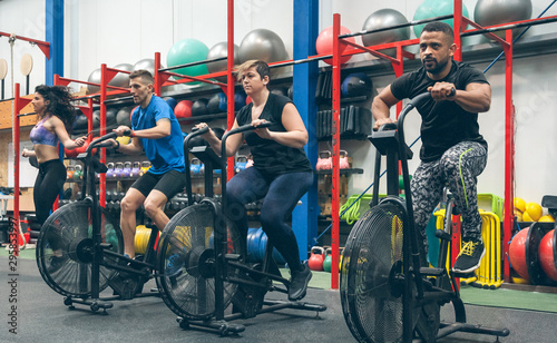 Group of athletes doing air bike at the gym photo