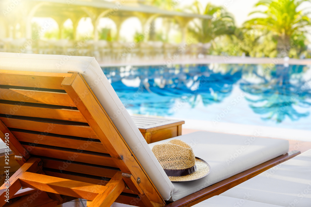 Lounger with sun hat and swimming pool in luxury resort - obrazy, fototapety, plakaty 