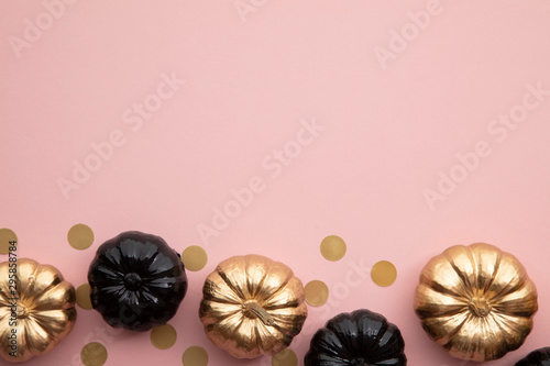 Gold and black pumpkins on pastel pink. Flat lay thanksgiving composition