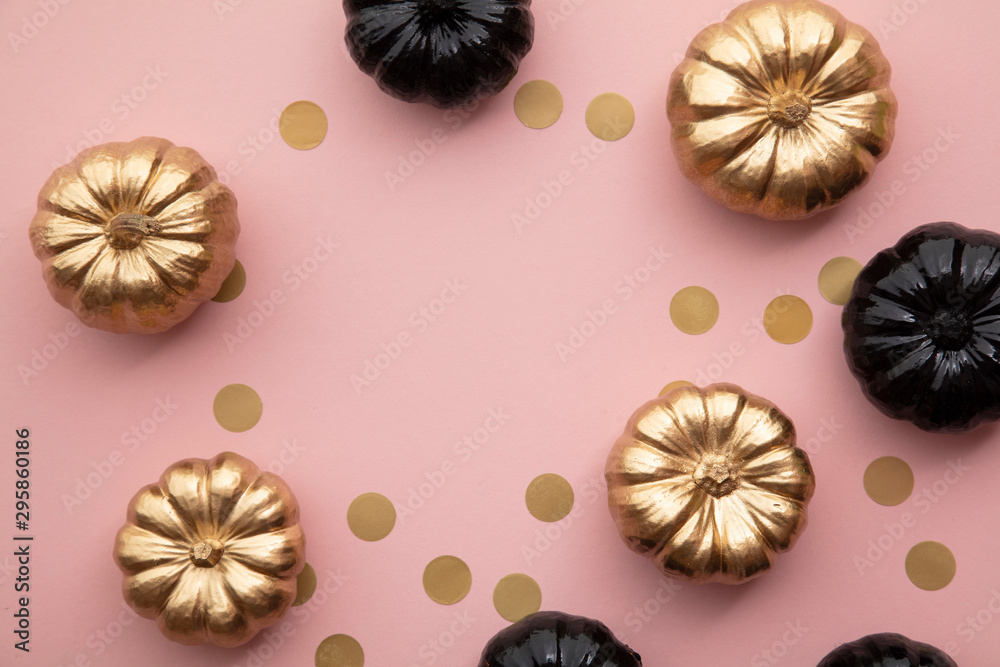 Fototapeta premium Gold and black pumpkins on pastel pink. Flat lay thanksgiving composition