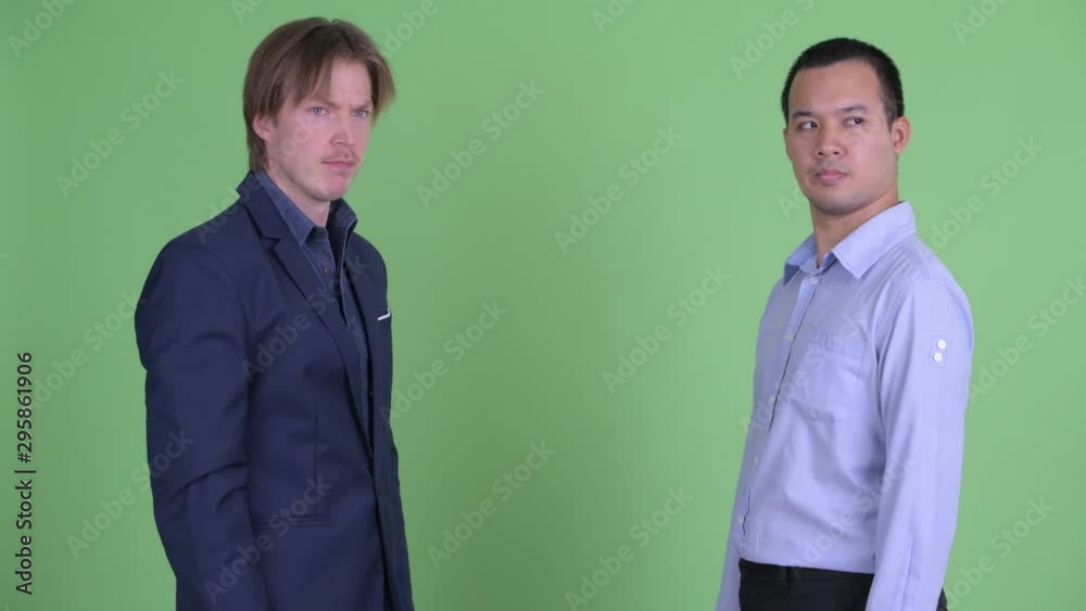 Two frustrated multi ethnic businessmen shaking hands together
