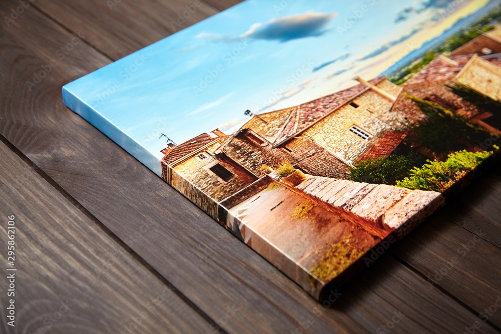 Canvas photo print on brown wooden background. Side view of colorful photography with gallery wrap. Photo printed on glossy canvas closeup