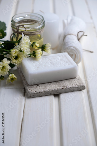 Obraz na płótnie Handmade soap with a pattern lies on the table. On a white table is handmade soap, flowers and olive oil. Collection of items for the bathroom w salonie