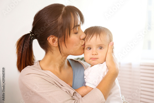 Portrait of young mother taking care of her little son at home. Beautiful female with straight brunette hair playing with child at living room. Close up, copy space, background.