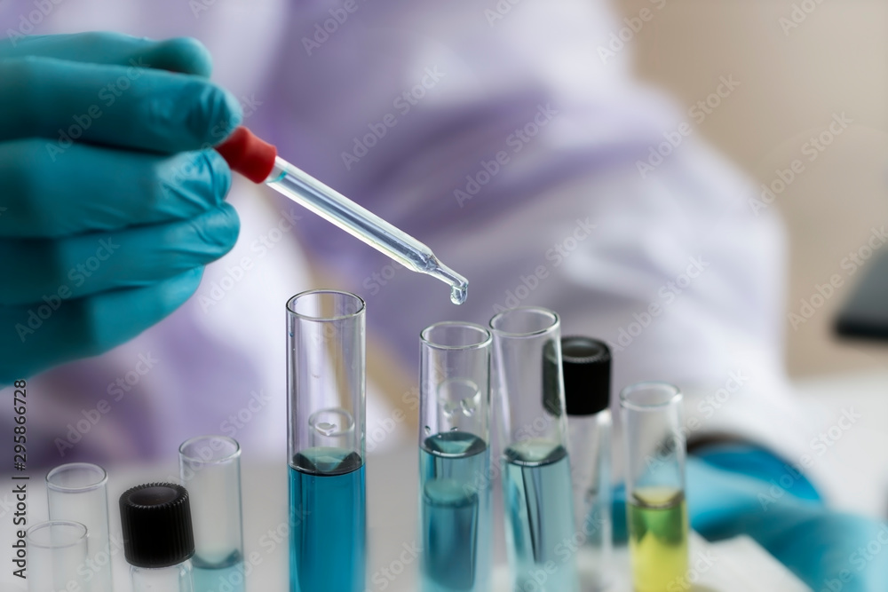 Fototapeta premium Laboratory concept; Scientist use dropper to transfer chemical reagent to test tube. He observe the chemical reaction in laboratory.