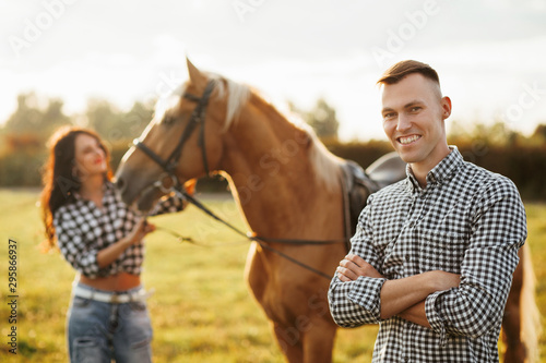 Portrait of happy loving couple spending time with horses on ranch © VAKSMANV