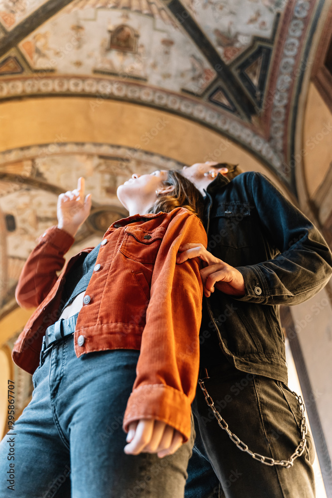 Vertical photo of a young couple contemplating the painted frescoes of a dome