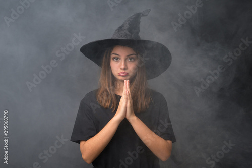 Girl with witch costume for halloween parties over isolated dark background pleading © luismolinero