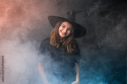 Young witch holding black and orange air balloons for halloween parties