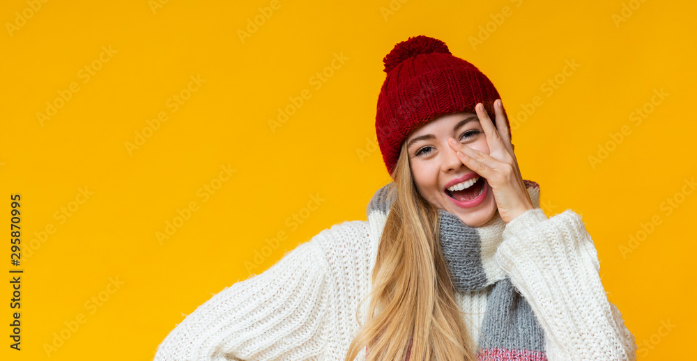 Joyful blonde girl posing over yellow studio background