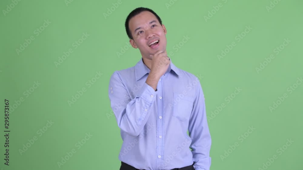 Studio shot of happy Asian businessman thinking and looking up Studio shot of happy Asian businessman thinking and looking up