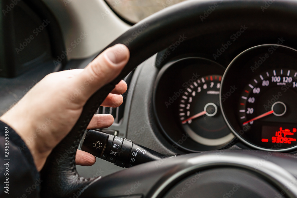 Driver's hand on steering wheel turns on turn signal
