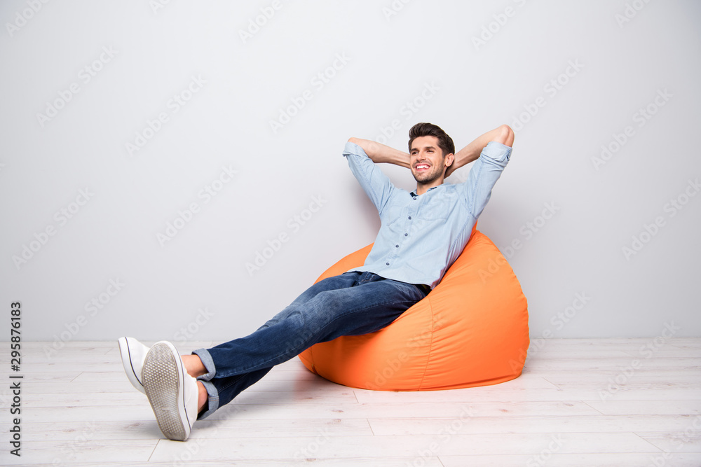 Turned full length body size photo of cheerful confident relaxing man sitting in chair thinking guessing smiling toothily having rest fun isolated over grey color background - obrazy, fototapety, plakaty 