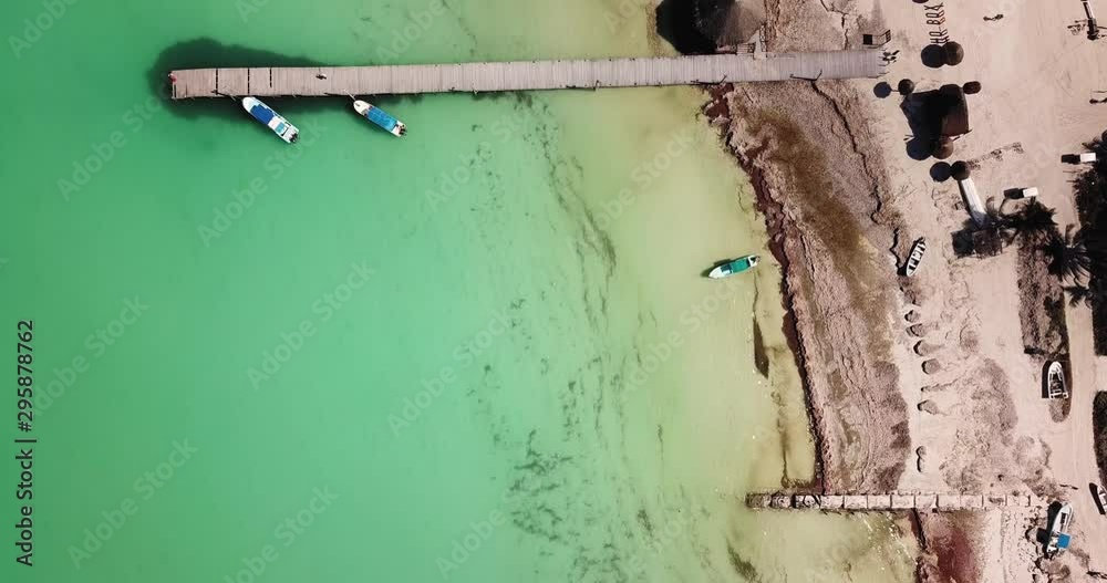 Top view on white caribbean sand beach with turquoise water and a dock with boats Top view on white caribbean sand beach with turquoise water and a dock with boats