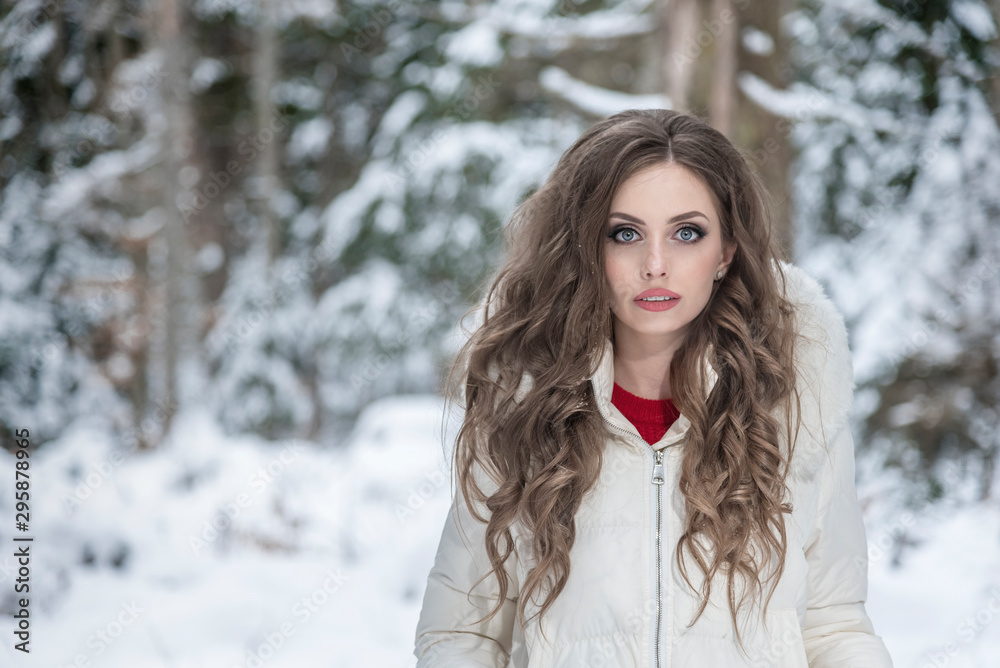 Beautiful young girl in a snowy winter forest.