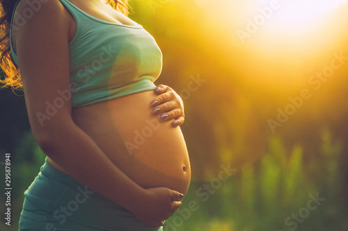Adult pregnant woman on against the backdrop of the sunset in the park. 9 months of pregnancy and childbirth. photo