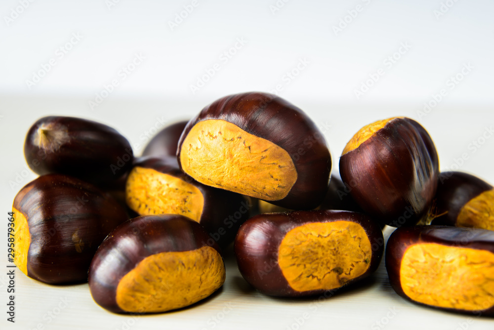 Fototapeta premium Castagne mature appena raccolte su tagliere bianco