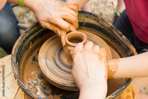 A close up view on ceramic production process on potter's wheel with children. Clay crafts with kids concept.