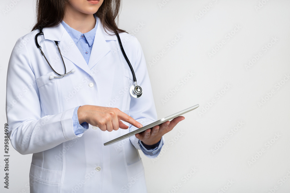 Unrecognizable Lady Doctor Using Tablet Computer Standing In Studio, Cropped Unrecognizable Lady Doctor Using Tablet Computer Standing In Studio, Cropped