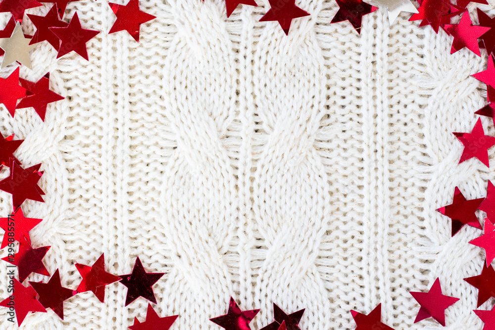 White knitted carpet closeup with red stars around the perimeter place for text. Textile texture off white background. Detailed warm yarn background. Knit cashmere beige wool. top view