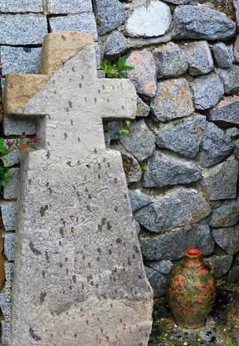 an old stone cross and a clay pot