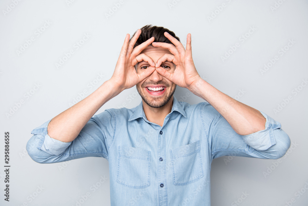Portrait of positive funny funky guy have rest relax fooling with his careless dream dreamy friends make binoculars with fingers ok sign wear casual style clothes isolated over grey color background Portrait of positive funny funky guy have rest relax fooling with his careless dream dreamy friends make binoculars with fingers ok sign wear casual style clothes isolated over grey color background