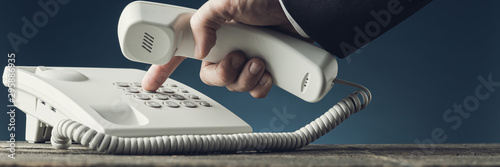 Wide view image of businessman dialing telephone number photo