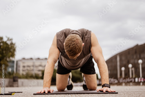 Young athletic man doing workout. Fitness outdoors. Push ups. Urban background.