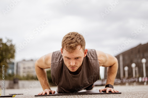 Young athletic man doing workout. Fitness outdoors. Push ups. Urban background. © Rymden