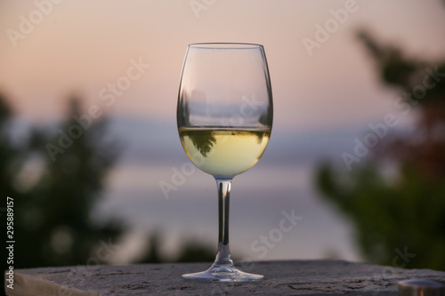 The glass of white wine and tropical sunset with sea