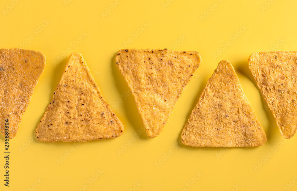 Mexican snack nachos lies in a row on a yellow background, top view, flat lay, copy space.