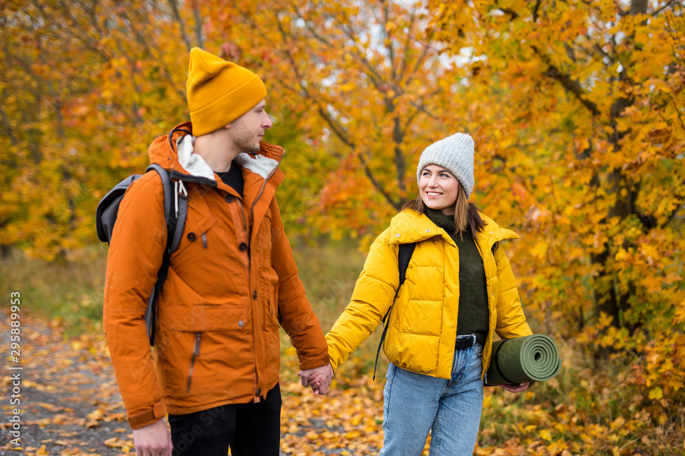 young couple in love walking in forest with backpacks young couple in love walking in forest with backpacks