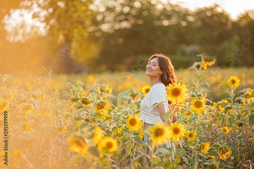Young Asian woman with curly hair in a field of sunflowers at sunset. Portrait of a young beautiful asian woman in the sun.