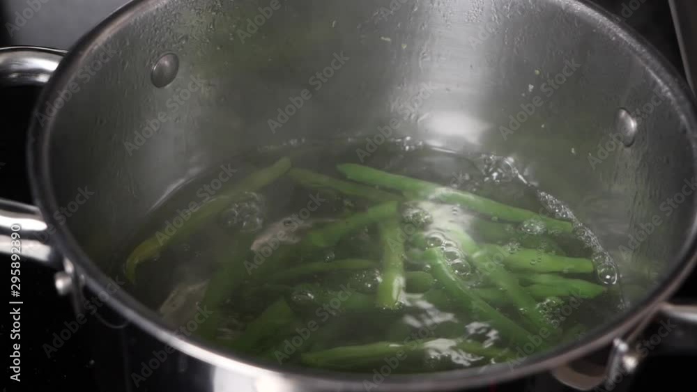 Placing a handful of beans into a boiling pot of water. Placing a handful of beans into a boiling pot of water.