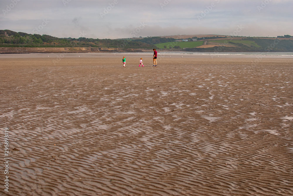 Obraz premium One man and a woman walking on sandy beach. One father and his daughter enjoying the day. family.