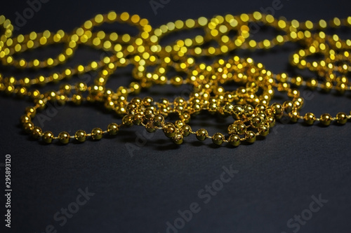 Gold Christmas garland on a black background. Top view. Copy space.Christmas frame for text. Black Christmas background with lights and bokeh.