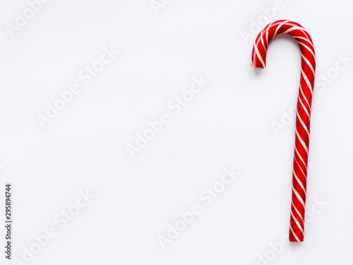 Christmas candy cone on white background. Colorful holiday sweet lollipop with copy space. Dessert wtih red and white stripes.