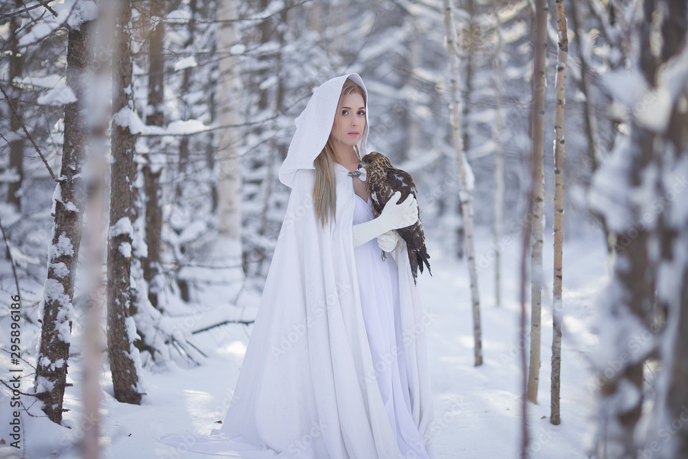  beautiful girl in a white dress walks in the winter forest