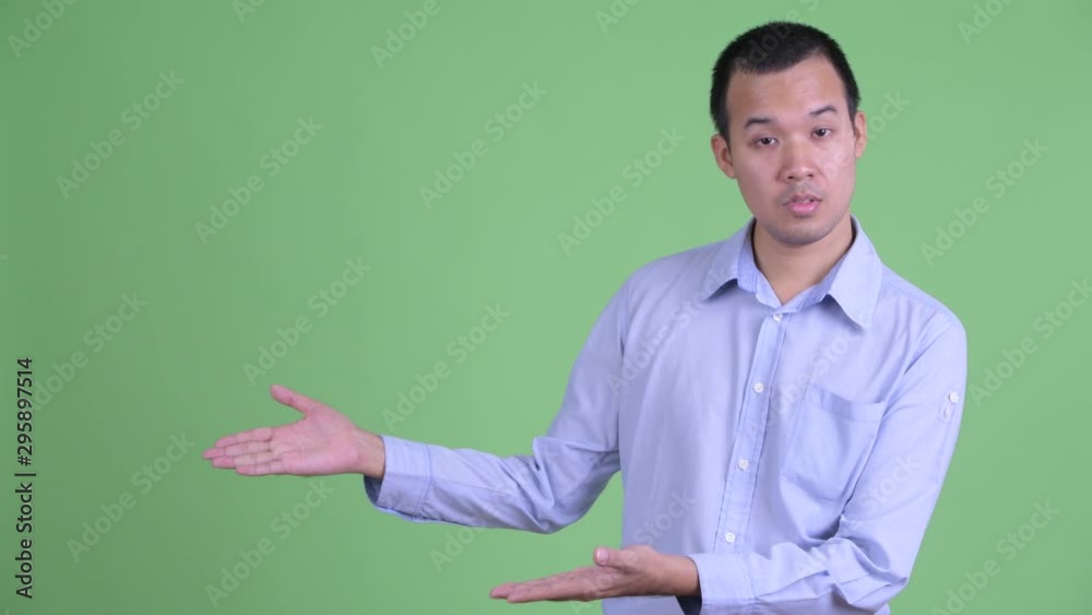 Stressed Asian businessman talking while showing something Stressed Asian businessman talking while showing something