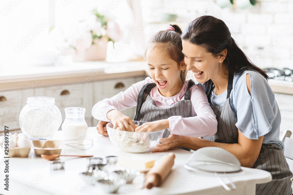 Cute little girl kneading the dough in bowl