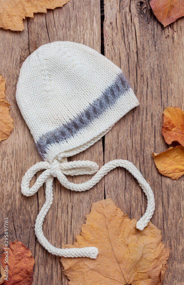 Hat for little children newborn on a wooden background Frame autumn leaves. Top view, flat lay.