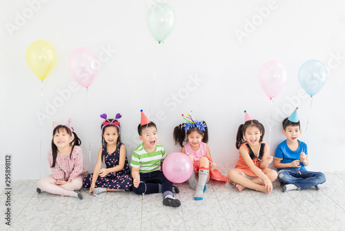 pretty asian children group standing and celebrate on gray background, they feeling happy in birthday party, they smile and play together, the holding Helium balloon, Christmas and new years party