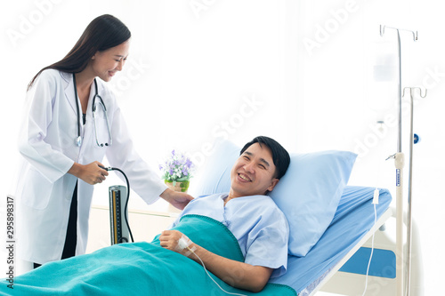 The doctor is the pressure gauge. The patient is lying in a hospital bed.female doctor with happy patient at the hospital.