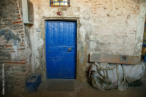 Old and worn blue wooden door with ironwork. Rustic blue door entrance to an old stone house