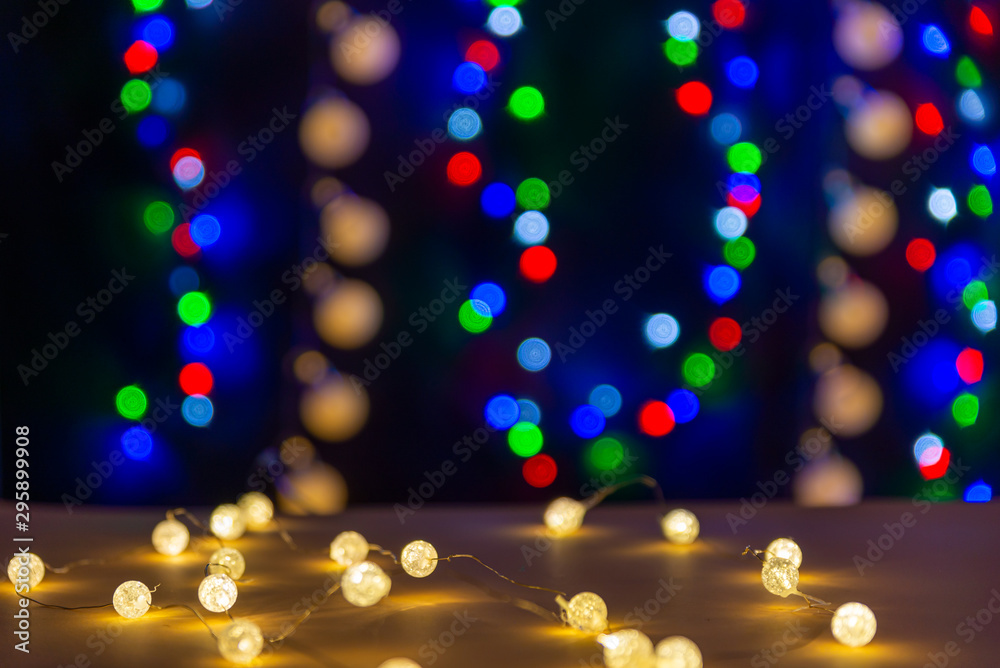 There are glowing lights on the table/background. There are different colors lights (blue, red, green, gold) on the background. Merry Christmas. Happy New Year 2020
