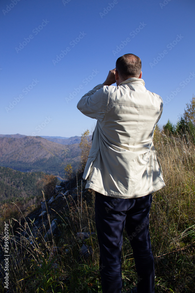 Man look through binoculars into the mountains