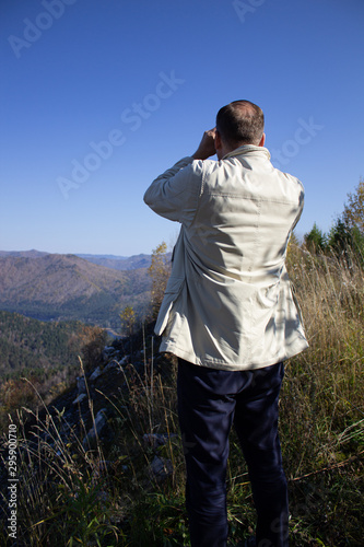 Man look through binoculars into the mountains © Анатолий Савицкий