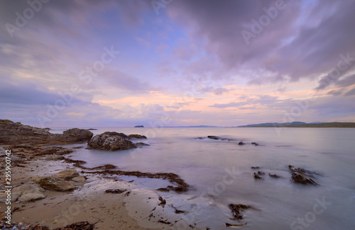 Mauve Sunset with wispy clouds on Pollan Beach, Inishowen, Ireland. Featuring rocks algues and sand with viiew of Malin Peninsula on horizon © joseph roland
